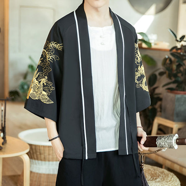 Homme portant un kimono noir avec broderies dorées de dragons sur les manches. Le kimono a des bordures blanches et est porté ouvert sur une chemise blanche à boutons.