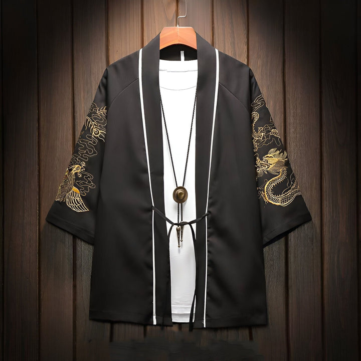 Veste kimono noire avec broderies de dragons dorés sur les manches, portée sur un t-shirt blanc. Détails de bordure blanche et pendentif décoratif. Mode asiatique, style décontracté.