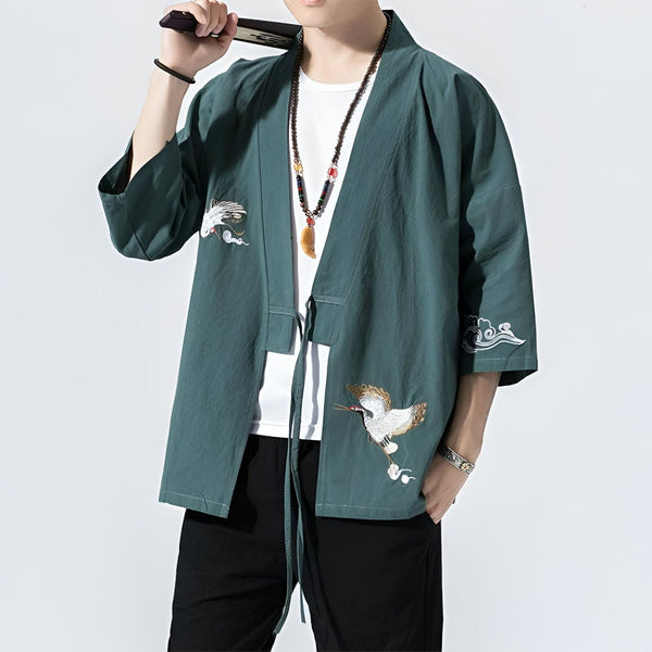 Homme portant un kimono vert avec des motifs de grues. Vêtements traditionnels japonais. Idéal pour un style unique et élégant. Découvrez notre collection de kimonos.