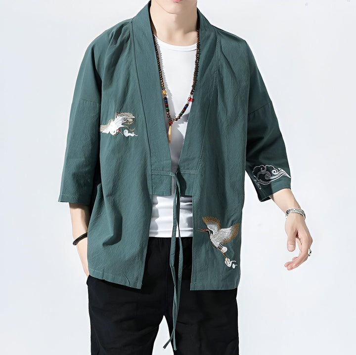 Homme portant un kimono vert avec broderies de grues et de nuages. Vêtements traditionnels japonais. Kimonos disponibles à l'achat.