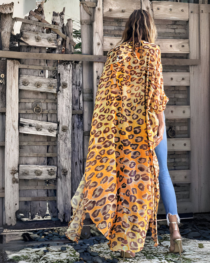 Femme portant un kimono long imprimé léopard, dos à la caméra devant une porte en bois rustique. Kimonos de style unique à vendre.