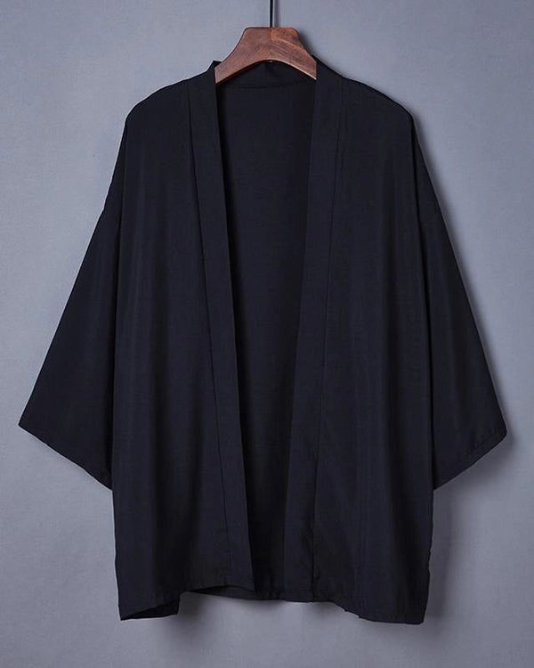 Kimono noir décontracté suspendu à un cintre en bois. Découvrez notre collection de kimonos pour homme et femme.