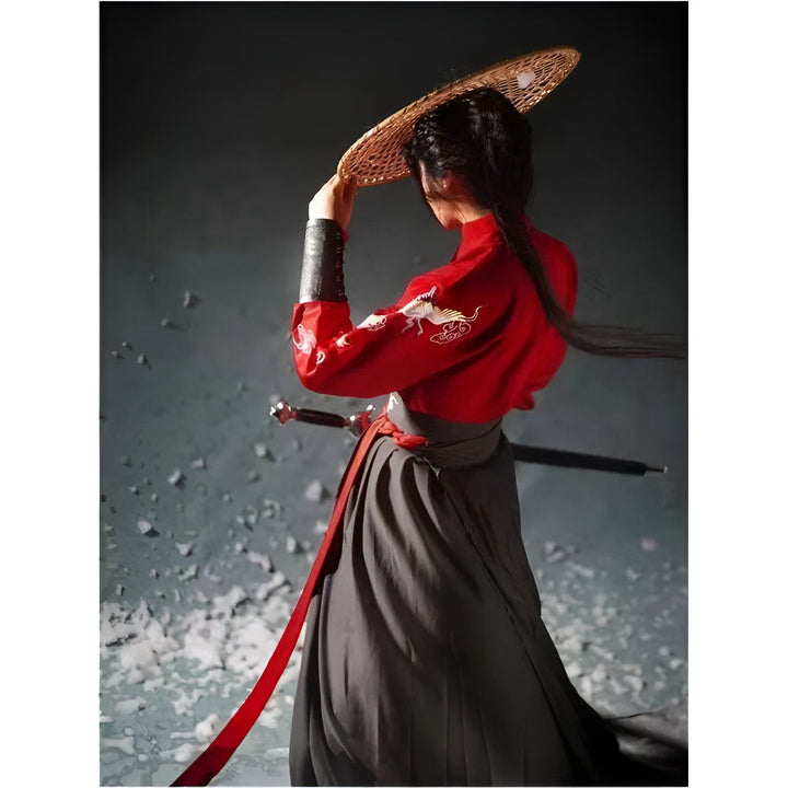 Image d'une personne portant un kimono rouge brodé et une jupe grise ample, avec un chapeau conique traditionnel. Épée visible, tenue d'inspiration asiatique. Kimono élégant à vendre.