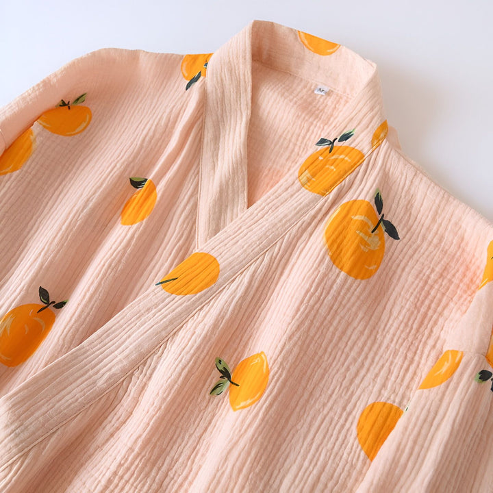 Gros plan d'un peignoir rose avec des motifs d'oranges. Le tissu a une texture gaufrée.