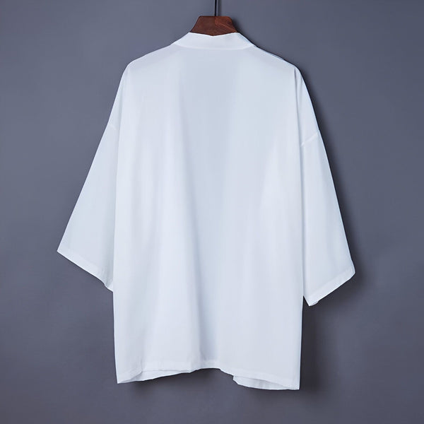Kimono blanc unisexe suspendu à un cintre. Vêtement traditionnel japonais, idéal pour un look décontracté et élégant. Découvrez notre collection de kimonos.