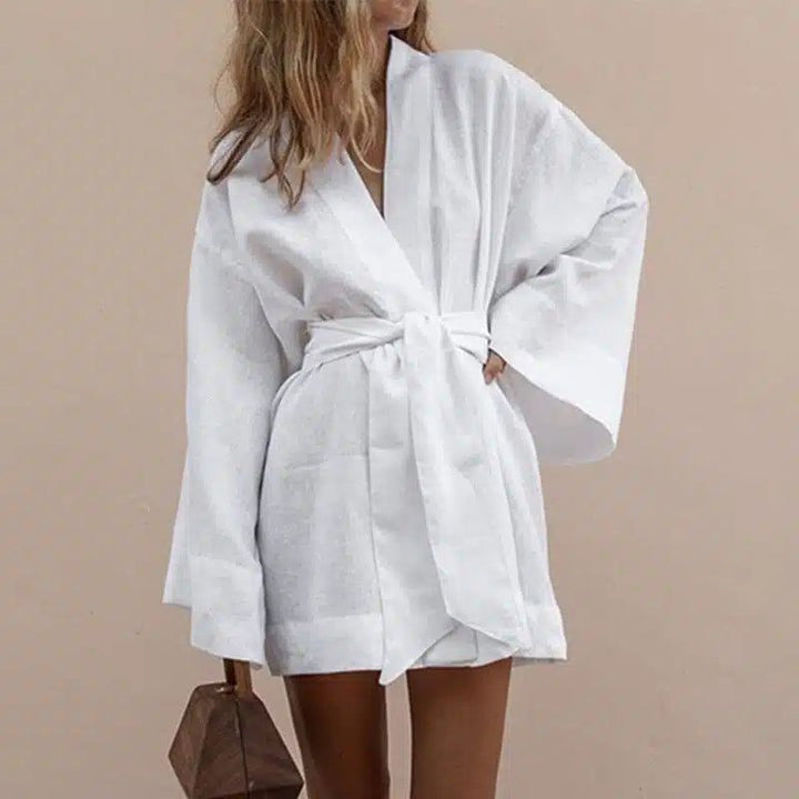 Femme portant un kimono blanc court avec une ceinture nouée. Kimono élégant et confortable, parfait pour la détente ou une sortie décontractée. Découvrez notre collection de kimonos uniques.