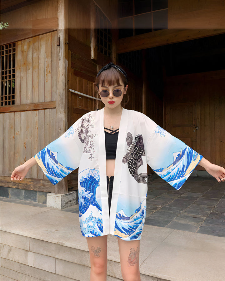 Femme portant un kimono blanc imprimé avec des vagues bleues et un poisson noir. Kimono de style japonais à vendre dans notre boutique en ligne. Mode kimono tendance et unique.