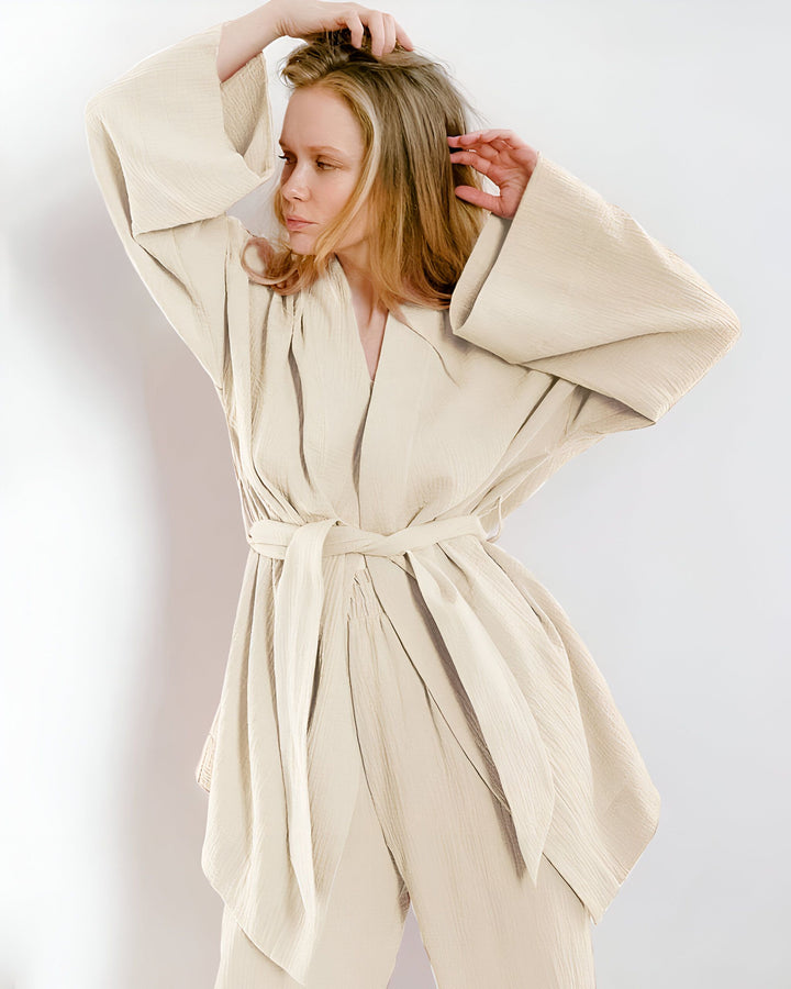 Femme blonde portant un kimono beige élégant. Vêtements kimono amples et confortables avec une ceinture nouée. Collection de kimonos tendances.
