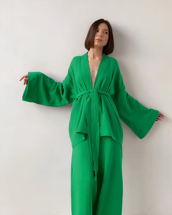 Femme portant un kimono vert émeraude avec des manches amples. Vêtements de détente confortables et élégants. Kimono disponible à l'achat.