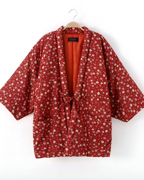 Kimono fleuri rouge suspendu sur un cintre. Vêtement traditionnel japonais avec motif floral. Découvrez notre collection de kimonos.