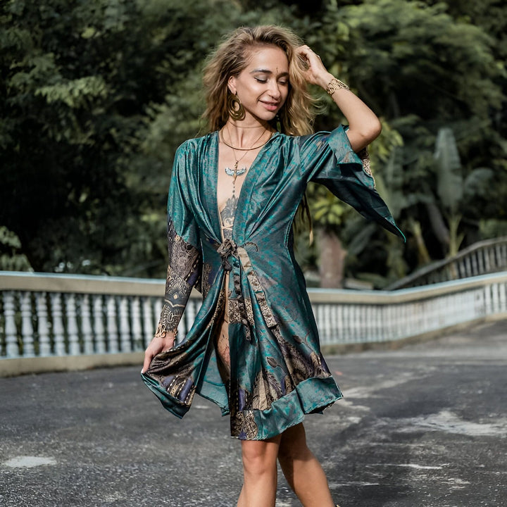 Femme portant un kimono turquoise à motifs. Vente de kimonos uniques en ligne. Kimono de créateur pour femme, style bohème chic, manches larges, tissu léger et fluide. Mode femme originale et élégante.