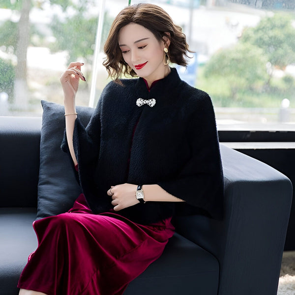 Femme élégante portant un kimono noir avec broche, assise sur un canapé. Kimono de notre boutique en ligne.