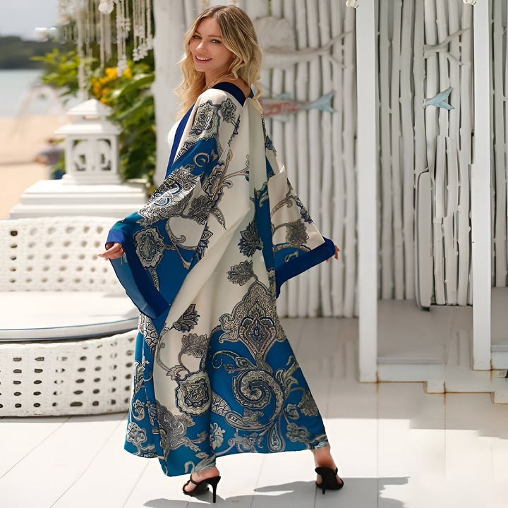 Femme souriante portant un kimono imprimé bleu et blanc sur la plage. Mode de plage décontractée et élégante. Parfaite pour les vacances d'été.