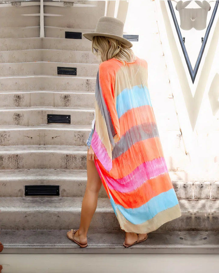 Femme portant un kimono coloré à rayures, chapeau et sandales. Elle descend un escalier. Kimonos pour femmes disponibles à l'achat.