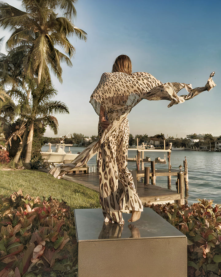 Femme portant un kimono à imprimé léopard au bord de l'eau. Élégance et style avec nos kimonos de haute qualité. Découvrez notre collection unique pour une allure sophistiquée.