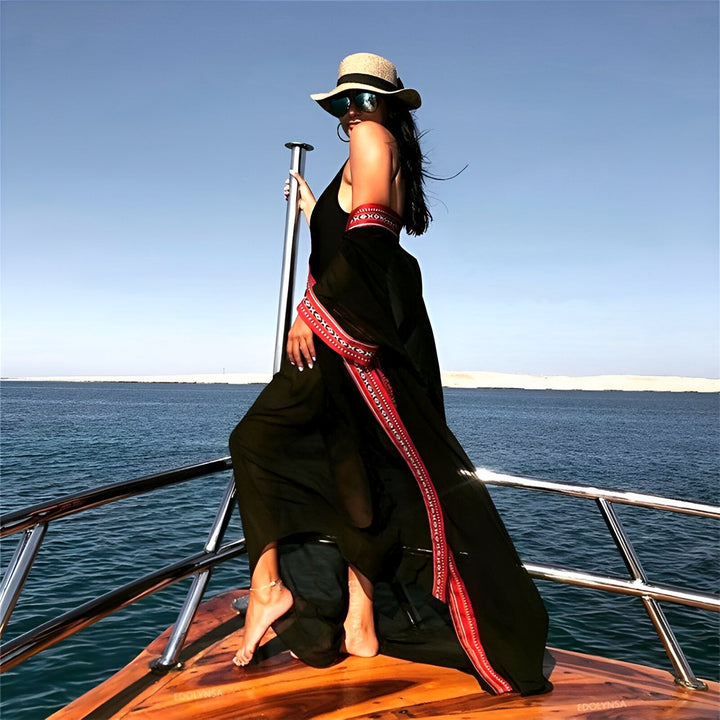 Femme élégante en kimono noir sur un bateau avec vue sur la mer. Découvrez notre collection de kimonos pour un look chic et estival.