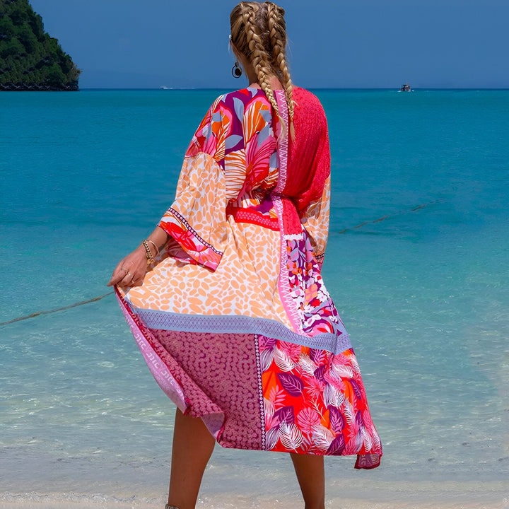 Femme de dos en kimono coloré sur une plage tropicale avec eau turquoise et ciel bleu. Elle a des tresses blondes.