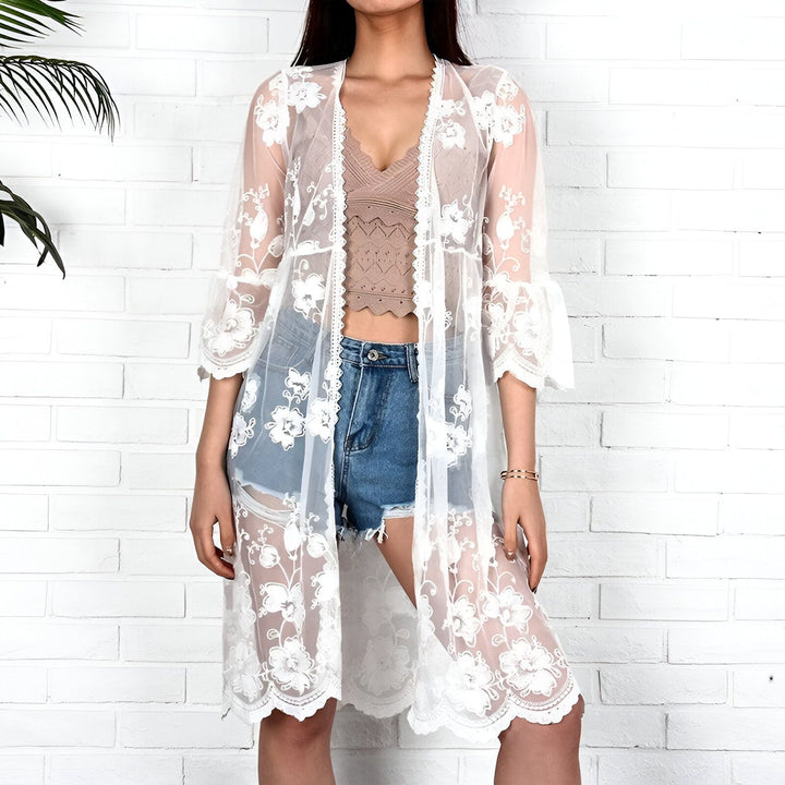 Femme portant un kimono blanc en dentelle à fleurs. Kimono transparent, style bohème, idéal pour la plage ou une tenue décontractée. Mode kimono en vente.