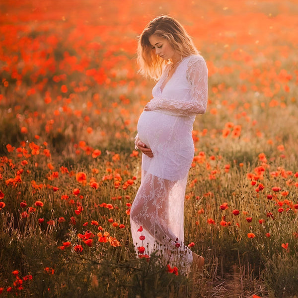 Femme enceinte en kimono blanc de dentelle dans un champ de coquelicots rouges. Vêtements de maternité élégants, kimono pour future maman.