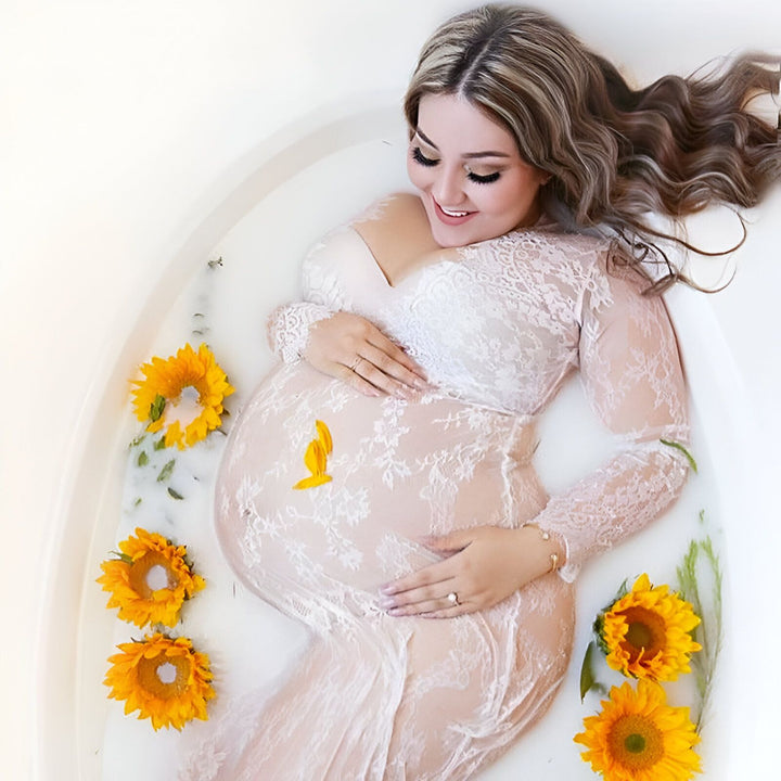 Femme enceinte en kimono de dentelle blanche dans un bain de lait avec des tournesols. Kimonos de maternité pour future maman.