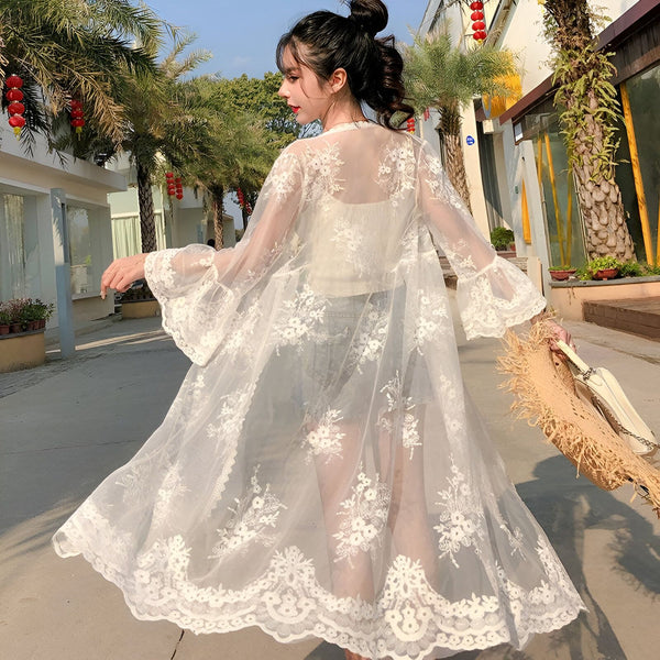 Femme portant un kimono blanc en dentelle, idéal pour l'été. Découvrez notre collection de kimonos.