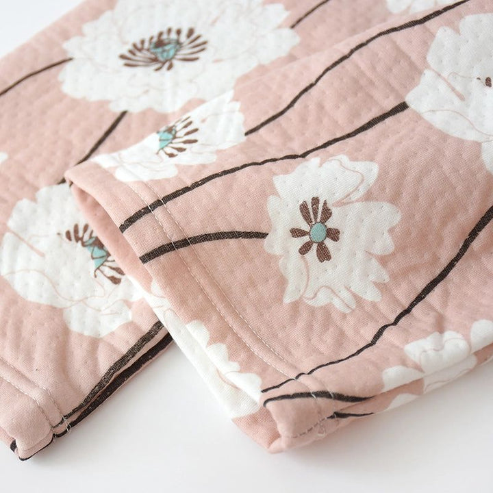 Détail d'un tissu de kimono rose pâle avec motif floral blanc. Texture douce, idéale pour un style japonais authentique et confortable. Motifs floraux délicats, parfait pour un kimono élégant.