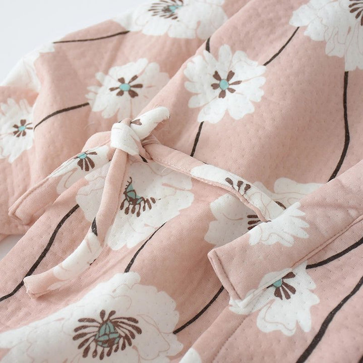 Détail d'un kimono rose à motifs floraux blancs. Ce kimono confortable est parfait pour se détendre avec style. Découvrez notre collection de kimonos uniques.