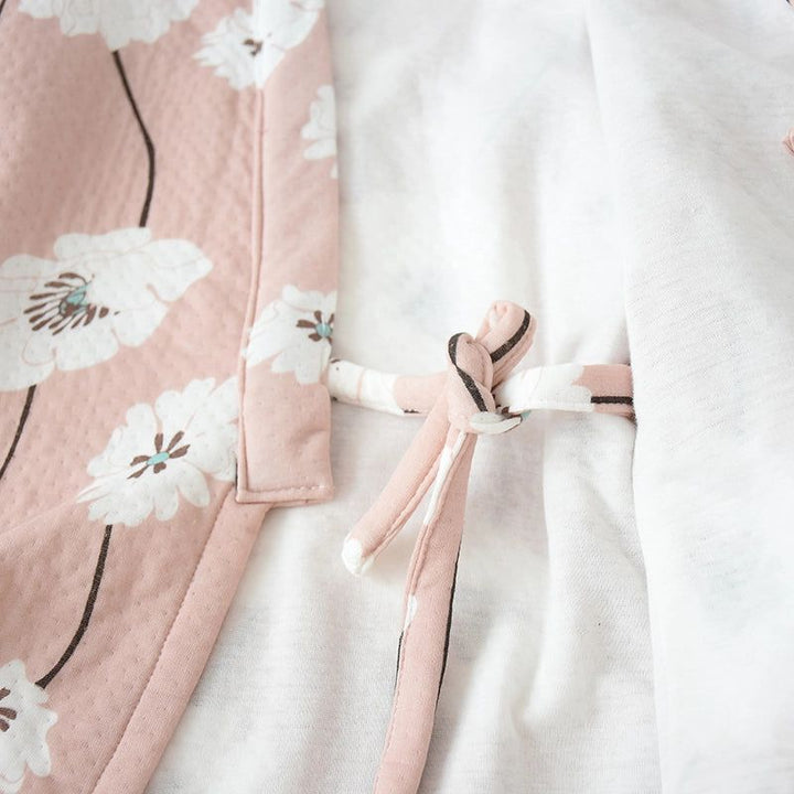 Détail d'un kimono rose poudré à motifs floraux blancs, noué avec des liens assortis. Vêtements japonais traditionnels et modernes à découvrir.