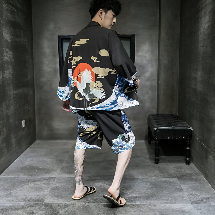 Homme portant un kimono noir et un short assorti avec motif grue, soleil rouge et vagues japonaises. Vêtements de style japonais.