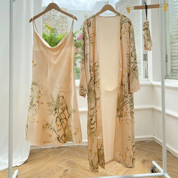 Ensemble kimono fleuri pêche. Comprend une robe nuisette à fines bretelles et un kimono long assorti, suspendus sur un portant. Idéal pour un look élégant et confortable. Découvrez notre collection de kimonos en ligne !