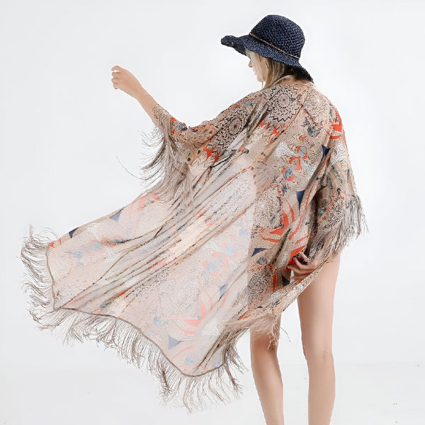 Femme portant un kimono beige à motifs avec des franges, chapeau bleu. Collection de kimonos pour femmes.