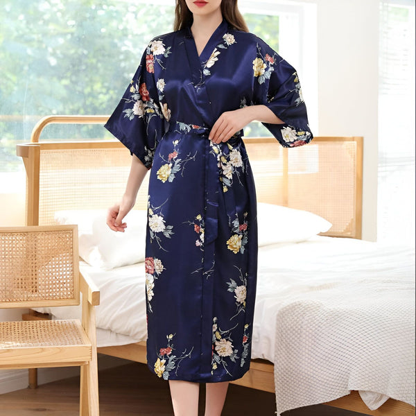 Femme portant un kimono bleu marine à motifs floraux. Peignoir en satin avec ceinture. Vêtement de détente élégant et confortable. Kimono pour femme, parfait pour la maison.