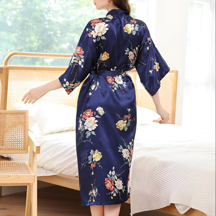 Femme portant un kimono bleu marine à motifs floraux, dos à la caméra. Vêtement de détente élégant avec ceinture assortie. Notre collection de kimonos pour femme.