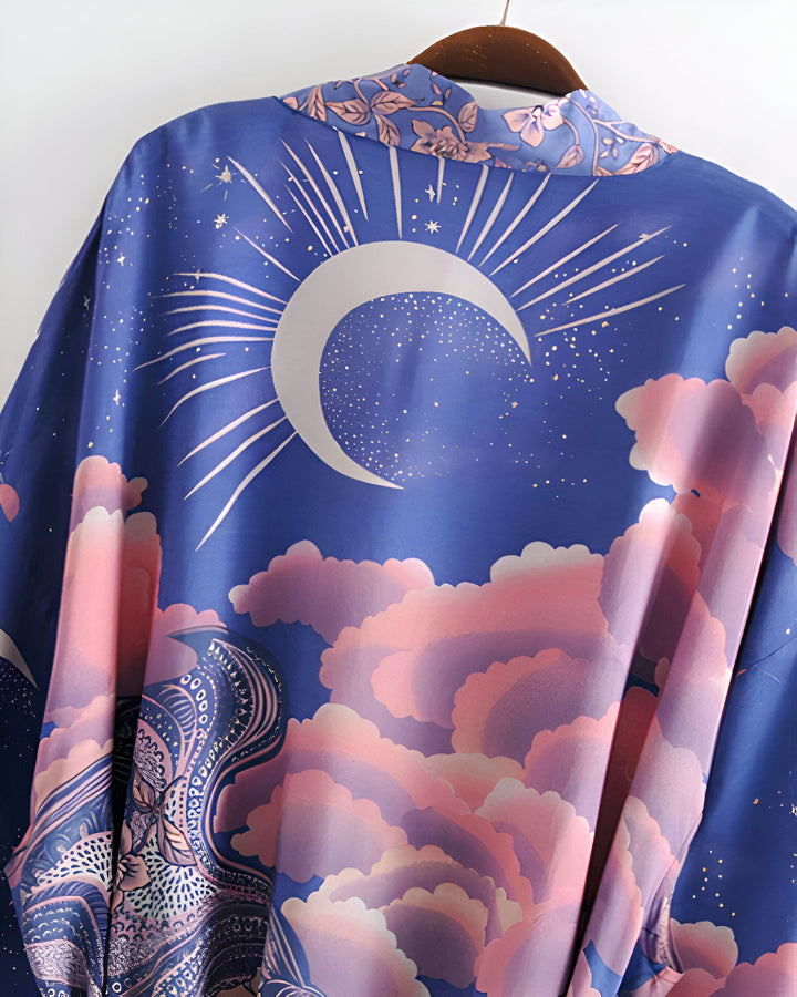 Kimono bleu avec motif lune, étoiles et nuages roses. Vêtement élégant et confortable. Parfait pour un look bohème chic. Découvrez notre collection de kimonos uniques.