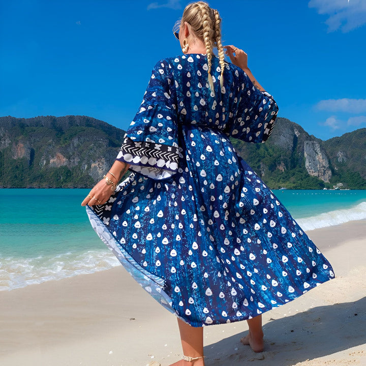 Femme portant un kimono bleu imprimé sur la plage. Dos de la femme blonde tressée. Kimono de plage ample et confortable. Vêtements de plage tendance et élégants. Achetez des kimonos uniques en ligne.