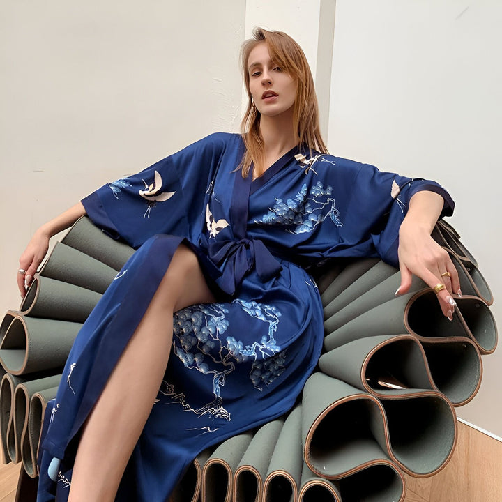 Femme portant un kimono bleu en soie avec motif de grues et de fleurs. Vêtements japonais traditionnels. Boutique de kimonos en ligne.