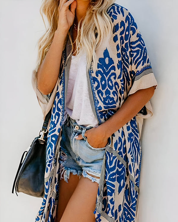 Femme portant un kimono bleu et beige à motifs, avec un short en jean délavé. Sac à main noir sur l'épaule. Idéal pour la boutique en ligne de kimonos.