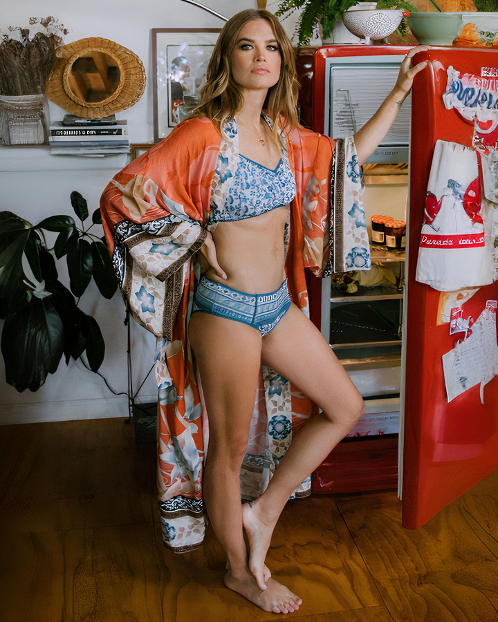 Femme portant un kimono fleuri devant un frigo vintage rouge. Style bohème chic, peignoir fleuri, intérieur décoré avec goût. Vente de kimonos en ligne.