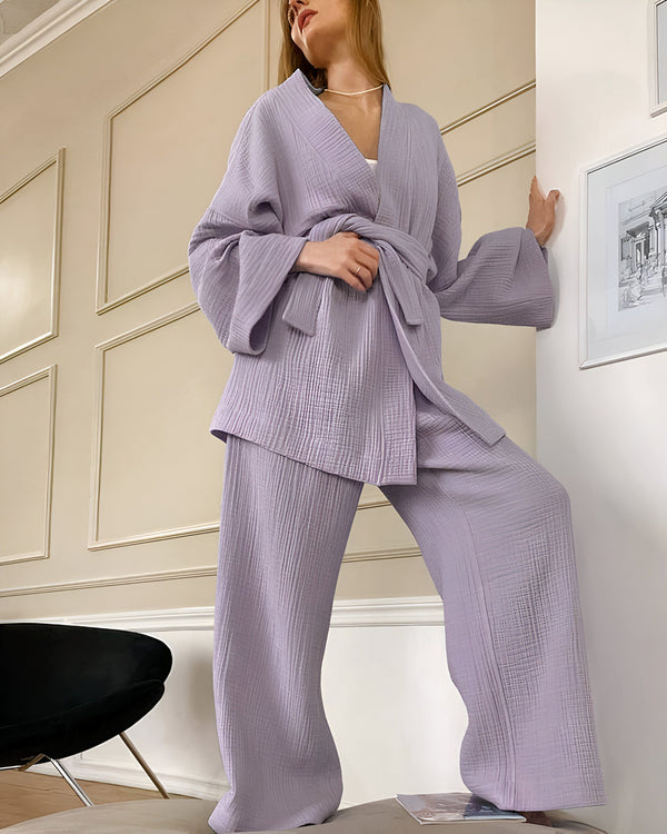 Femme portant un kimono lilas et un pantalon assorti. Ensemble kimono confortable et élégant, parfait pour se détendre à la maison ou comme tenue d'extérieur décontractée. Vêtements de style kimono tendance.
