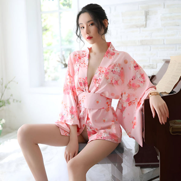 Femme portant un kimono rose à motifs floraux. Vêtements traditionnels japonais disponibles à l'achat. Élégance et confort incarnés dans ce kimono unique. Découvrez notre collection de kimonos.