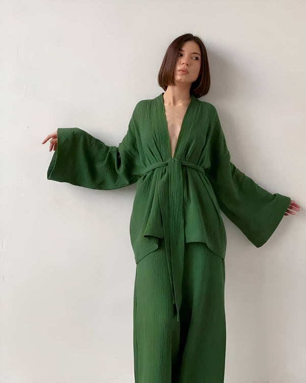Femme portant un kimono vert émeraude, manches larges, noué à la taille. Vêtement fluide et confortable. Collection de kimonos tendance.