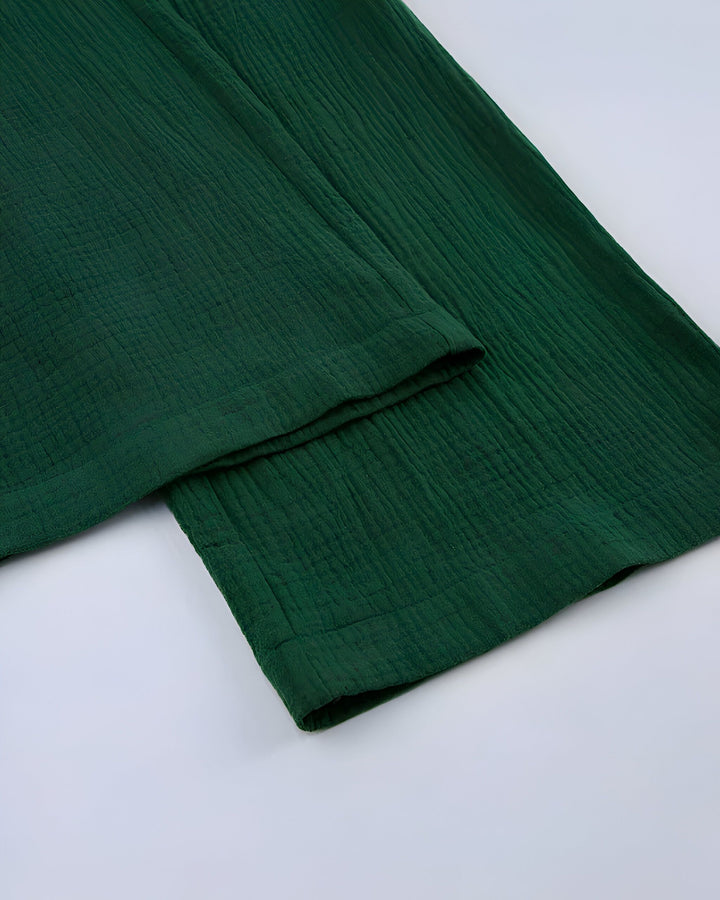 Détail d'un pantalon kimono vert émeraude en tissu texturé. Idéal pour un look confortable et élégant. Découvrez notre collection de kimonos et pantalons assortis.