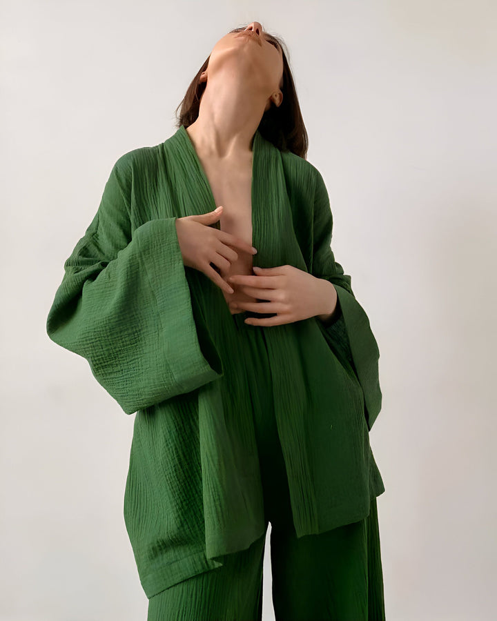 Femme portant un kimono vert en coton. Kimono ample à manches larges, pantalon assorti. Vêtements confortables et élégants. Mode kimono.