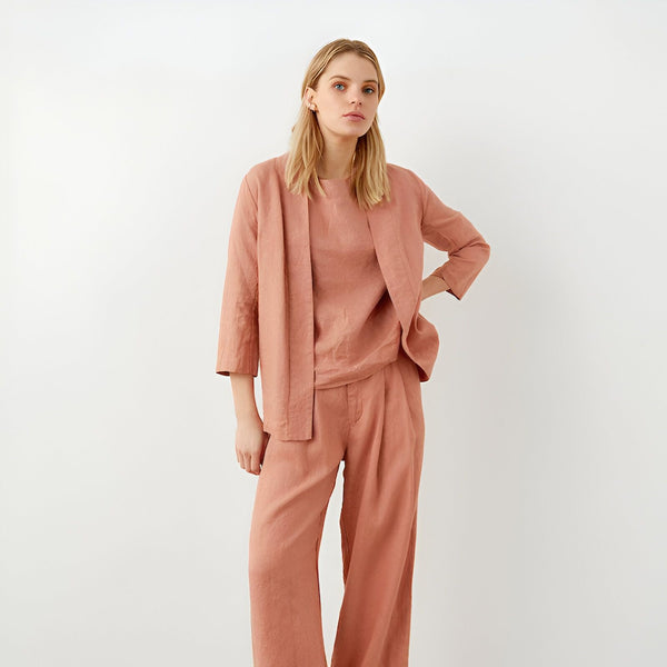 Femme portant un ensemble kimono rose pêche. Veste kimono ample et pantalon assorti. Vêtements kimono élégants et confortables.