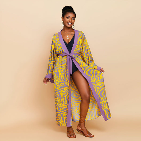Femme souriante portant un kimono long à motif zébré jaune et violet, avec une ceinture. Idéal comme vêtement de plage ou d'intérieur. Disponible dans notre collection de kimonos.