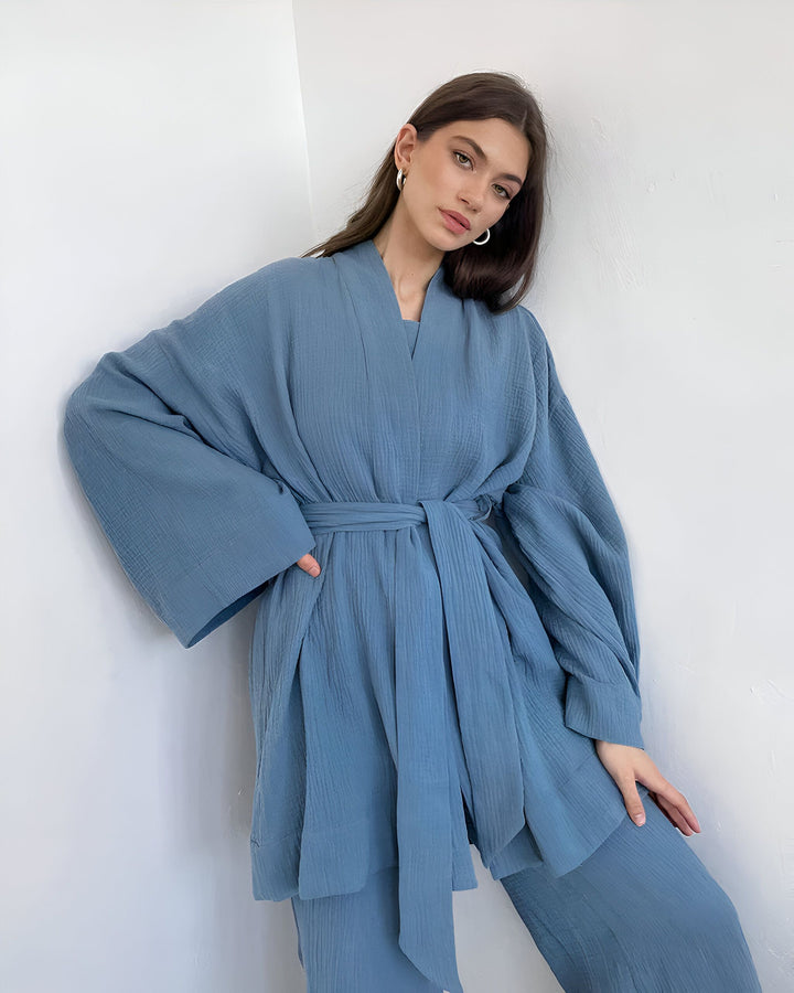Femme portant un kimono bleu clair en coton, pantalon assorti et ceinture nouée. Vêtements confortables et élégants. Kimonos de notre collection en vente.