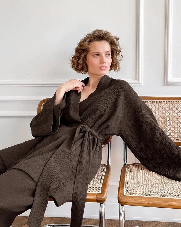 Femme portant un kimono marron confortable, assise sur une chaise. Découvrez notre collection de kimonos élégants et confortables.