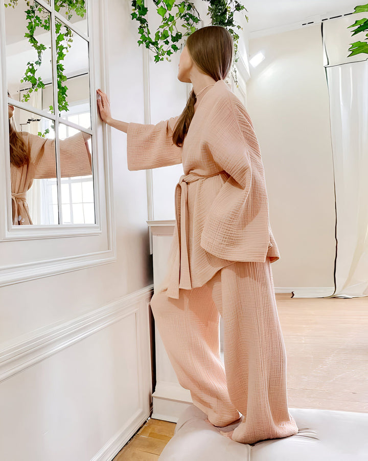 Femme portant un kimono rose doux, se regardant dans un miroir. Kimono confortable et élégant à vendre.