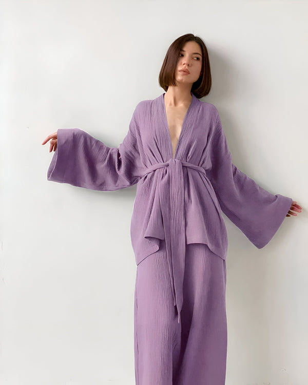 Femme portant un kimono violet ample avec un col en V profond et une ceinture nouée. Ensemble kimono confortable et élégant. Parfait pour se détendre à la maison ou pour une soirée spéciale.