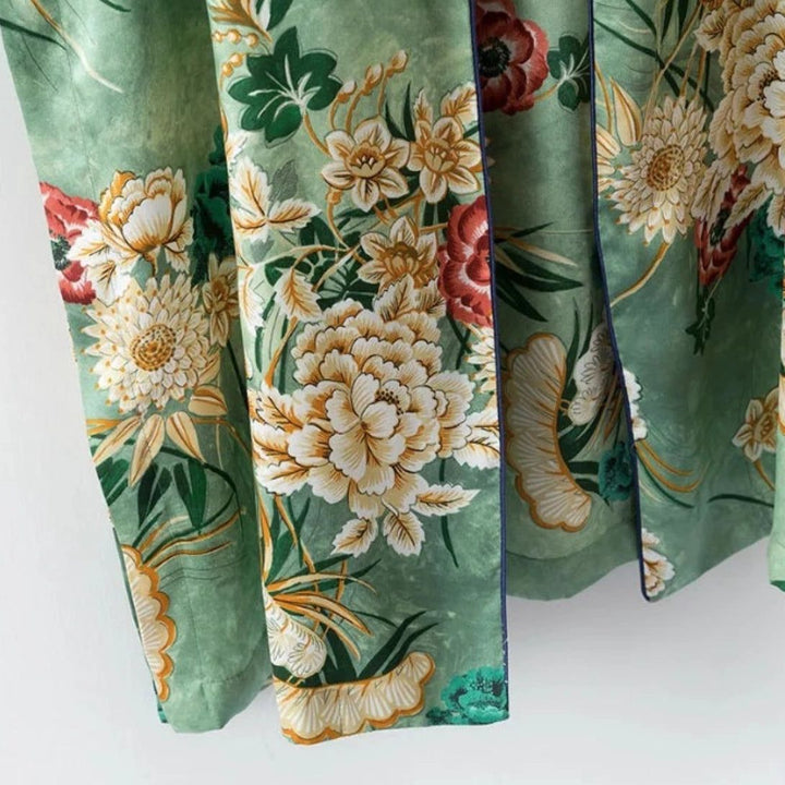 Détail d'un kimono vert à motifs floraux. Tissu imprimé avec des fleurs jaunes, rouges et blanches sur fond vert. Kimono élégant et confortable à porter.